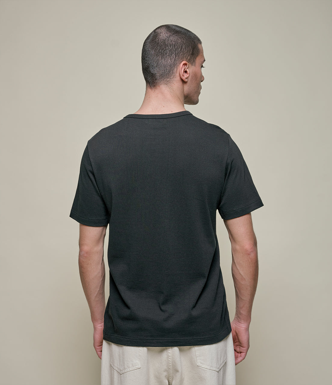 Man wearing a black t-shirt against a beige background