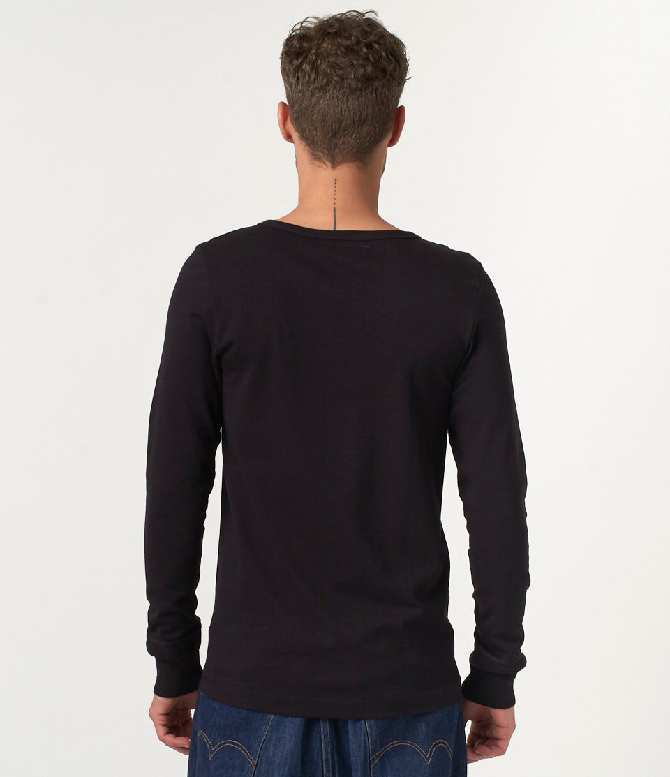 Person wearing a black long-sleeve shirt on a plain background
