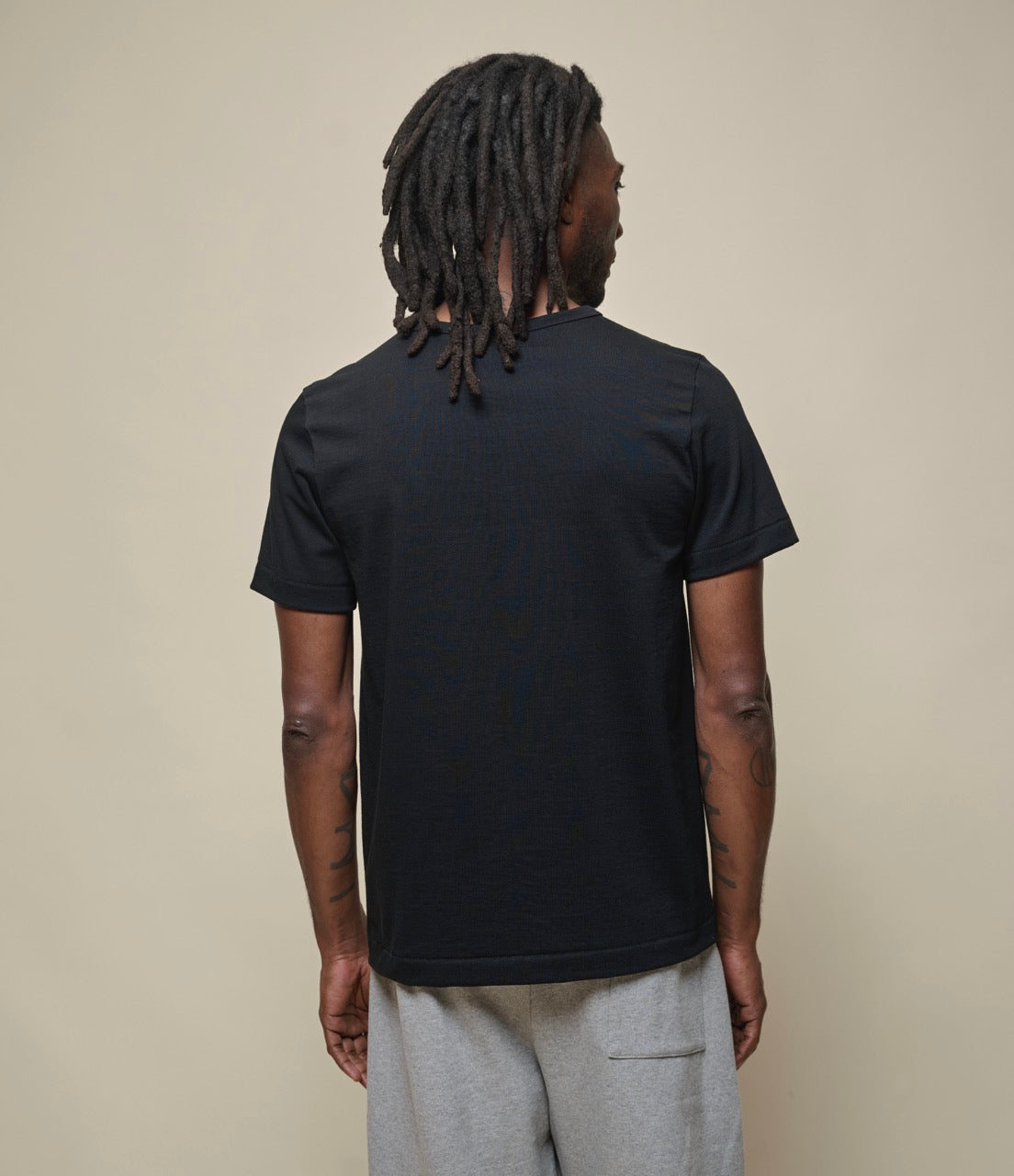 Person wearing a black t-shirt against a plain background
