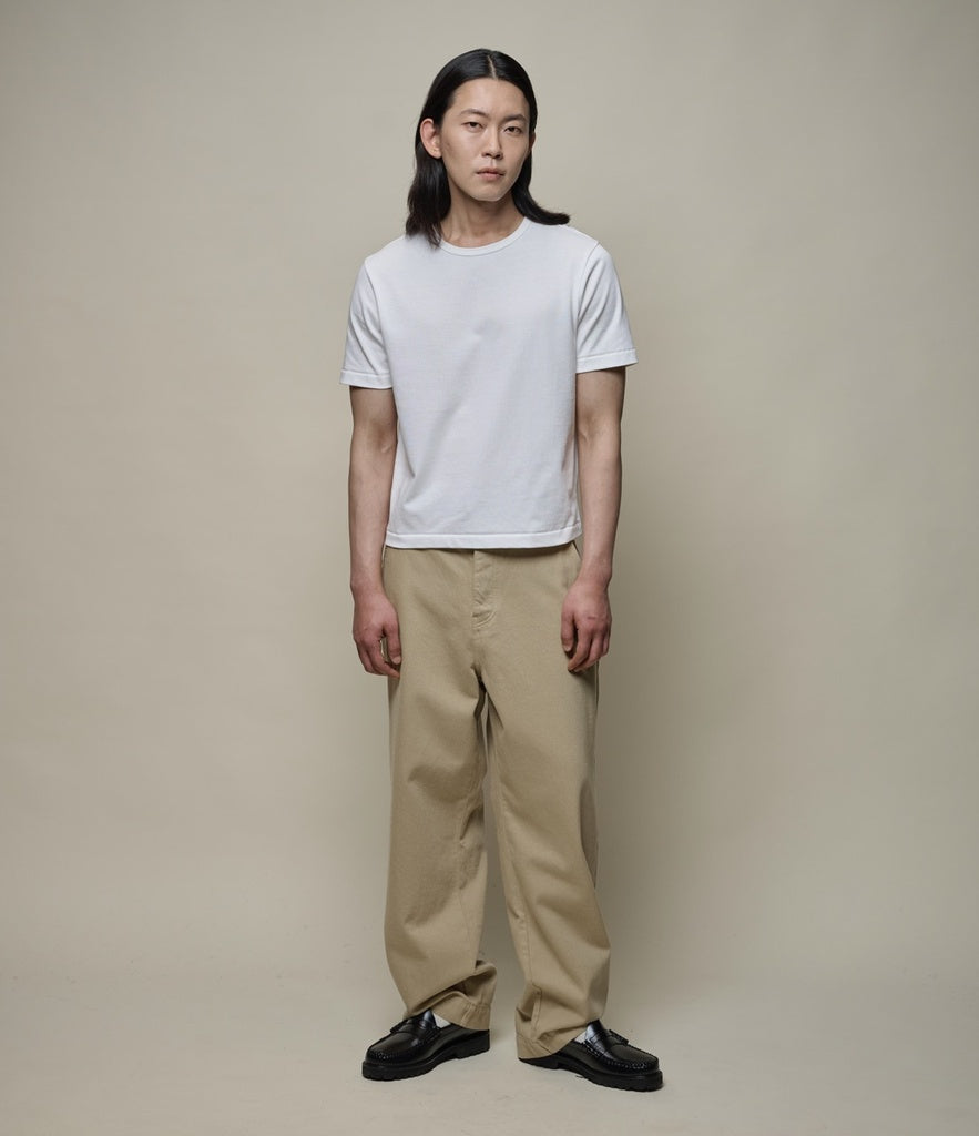 Man wearing cropped white T-shirt and beige pants