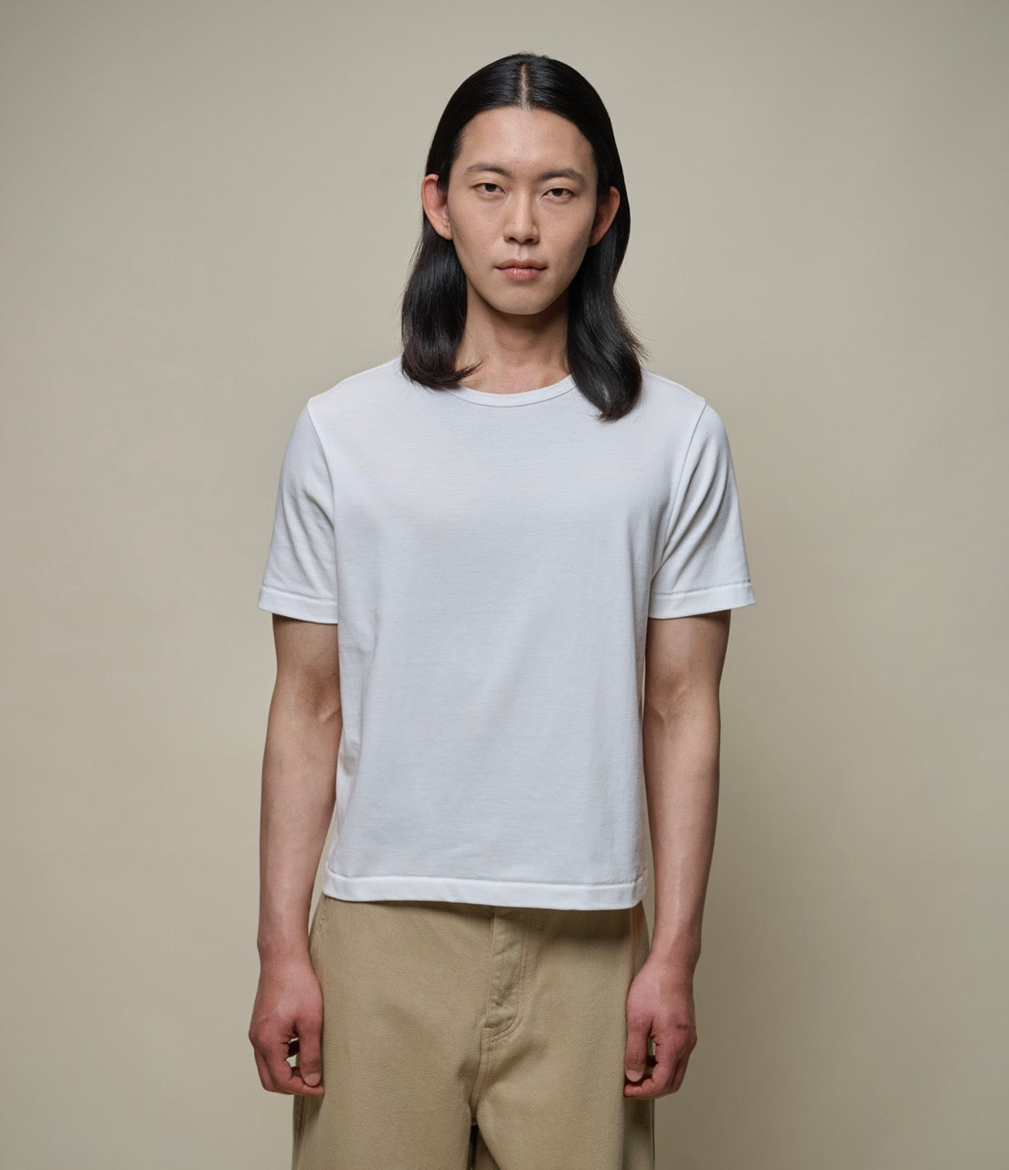 Man wearing a white, short-sleeved, round-neck t-shirt with a cropped fit.