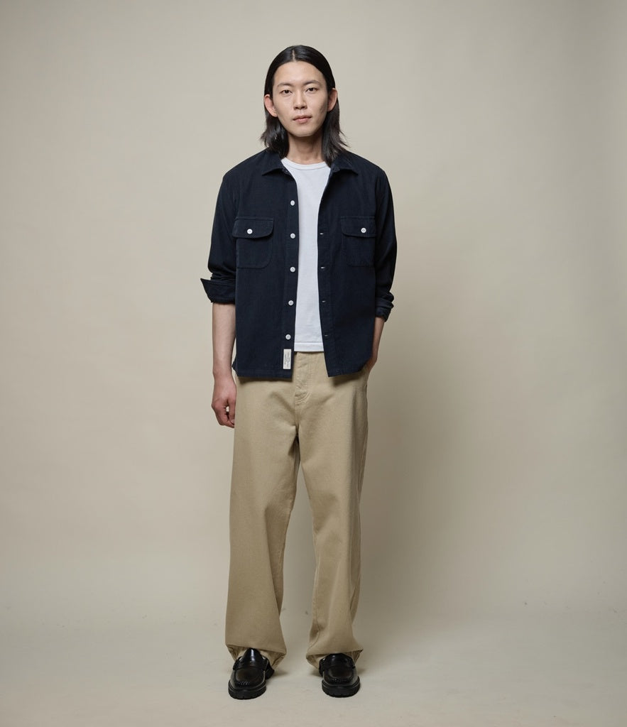 Man wearing white T-shirt, black corduroy shirt and beige twill pants