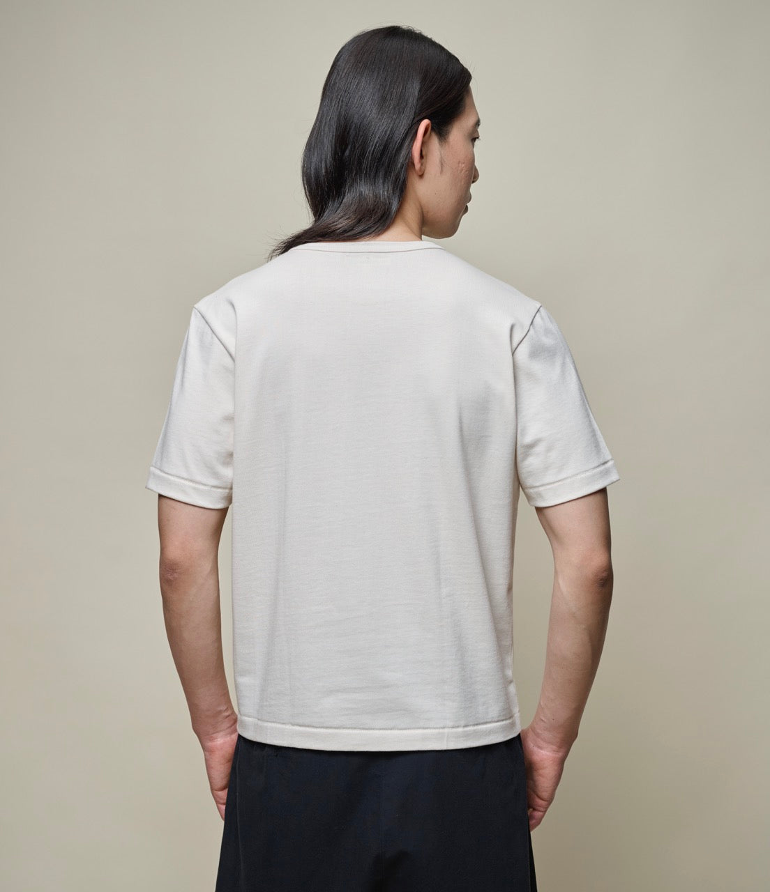 Man wearing a cropped nature T-shirt and black pants from behind