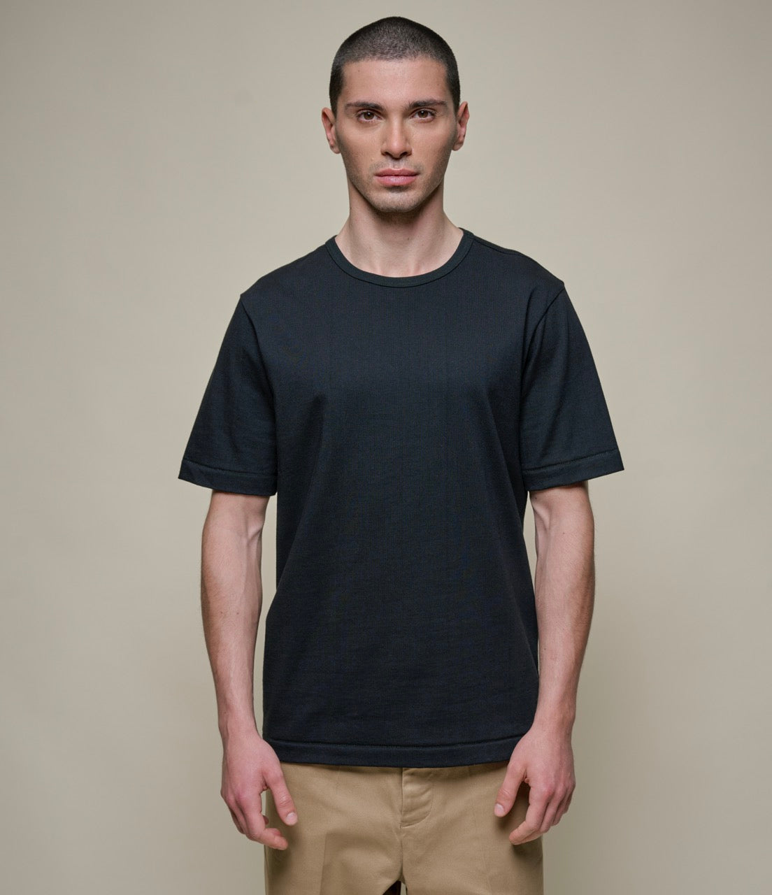 Man wearing a black classic-fit crew-neck T-shirt and beige pants.