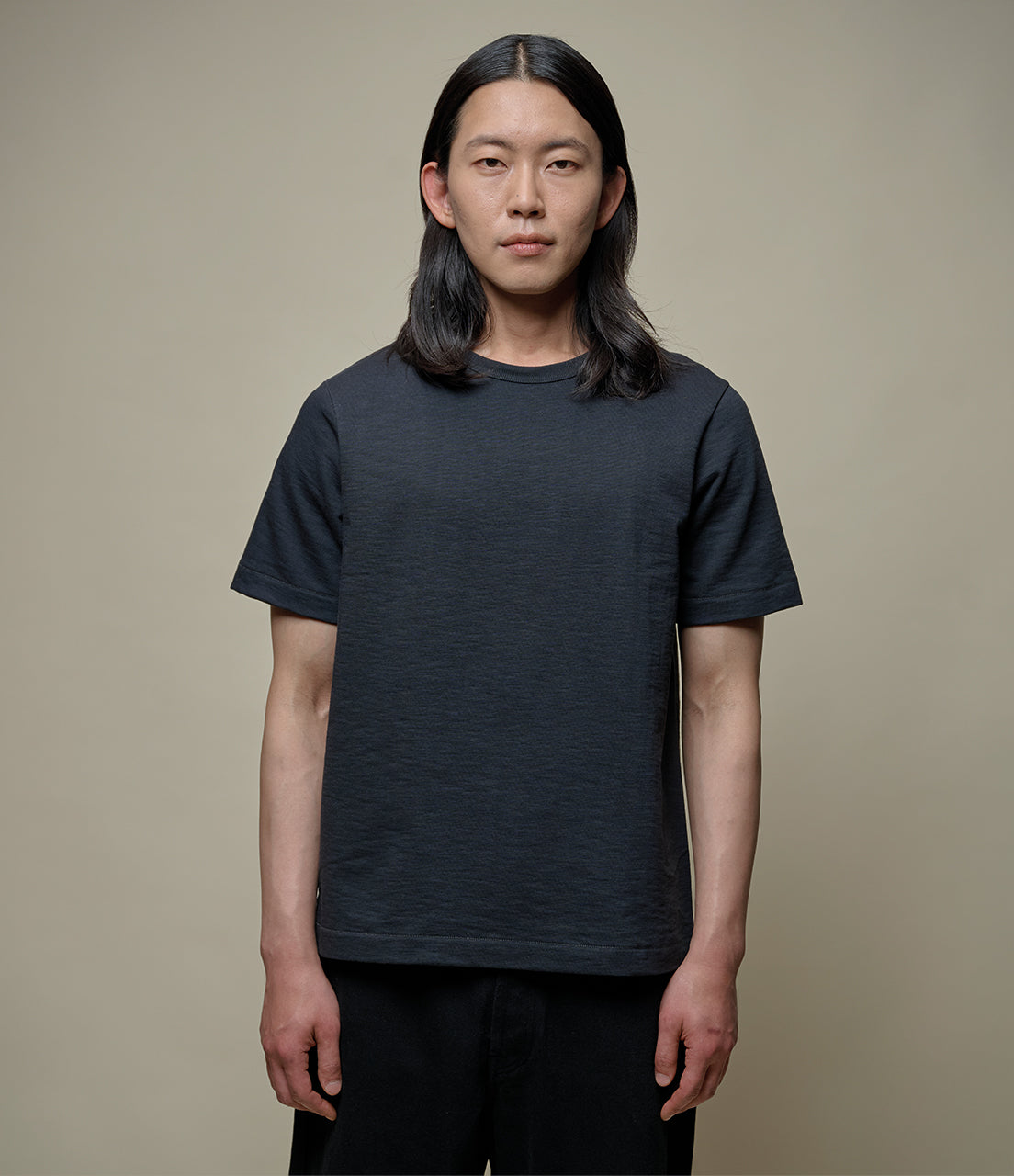 Person wearing a plain black t-shirt against a neutral background