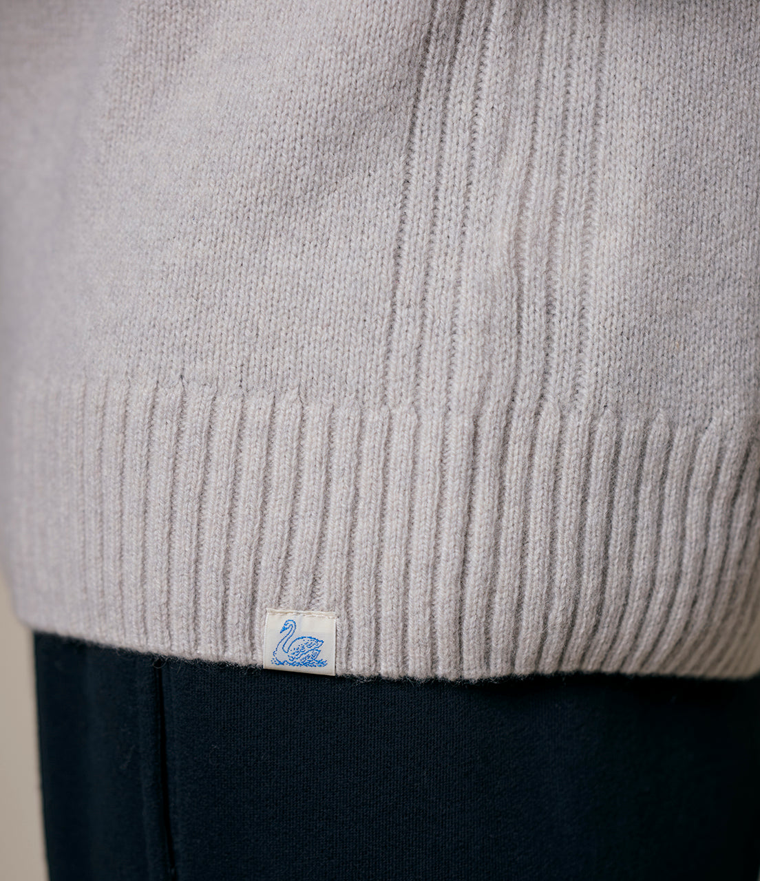 Close-up of a gray cashmere sweater with a brand label on a dark background