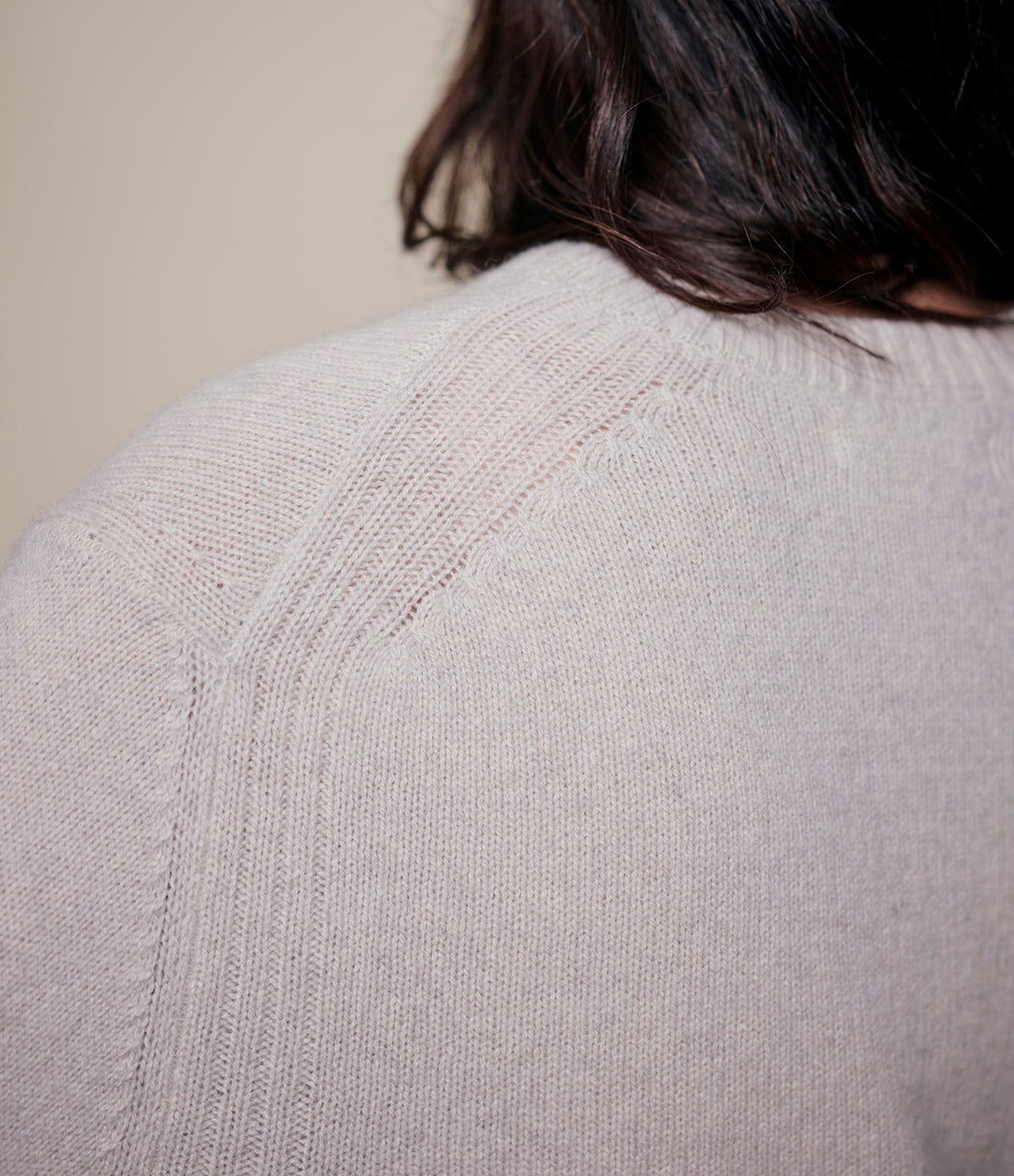 Close-up of a light gray cashmere sweater with a textured pattern on a neutral background