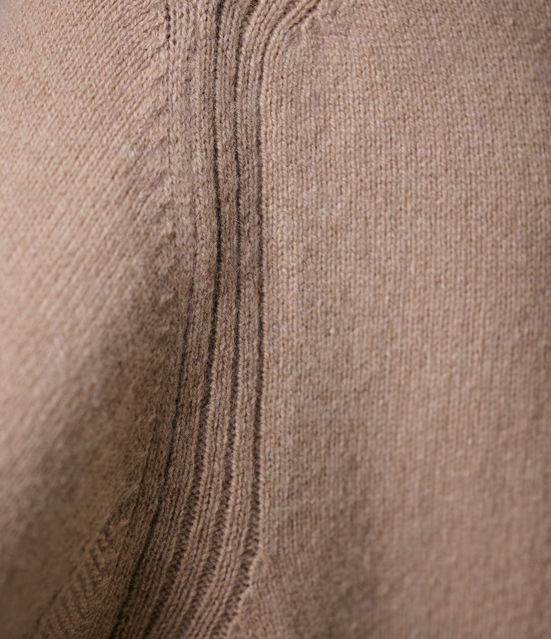 Close-up of a textured beige cashmere fabric with a subtle pattern