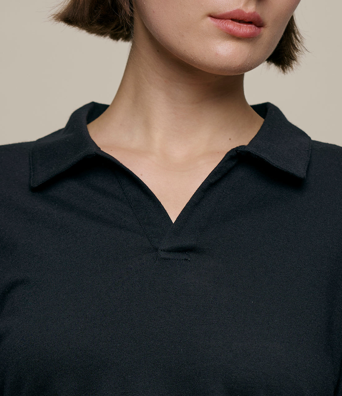 Close-up of a person wearing a black polo shirt against a neutral background