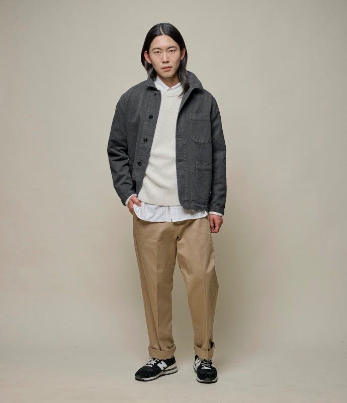 Person wearing grey twill jacket, beige sweater and beige chinos.