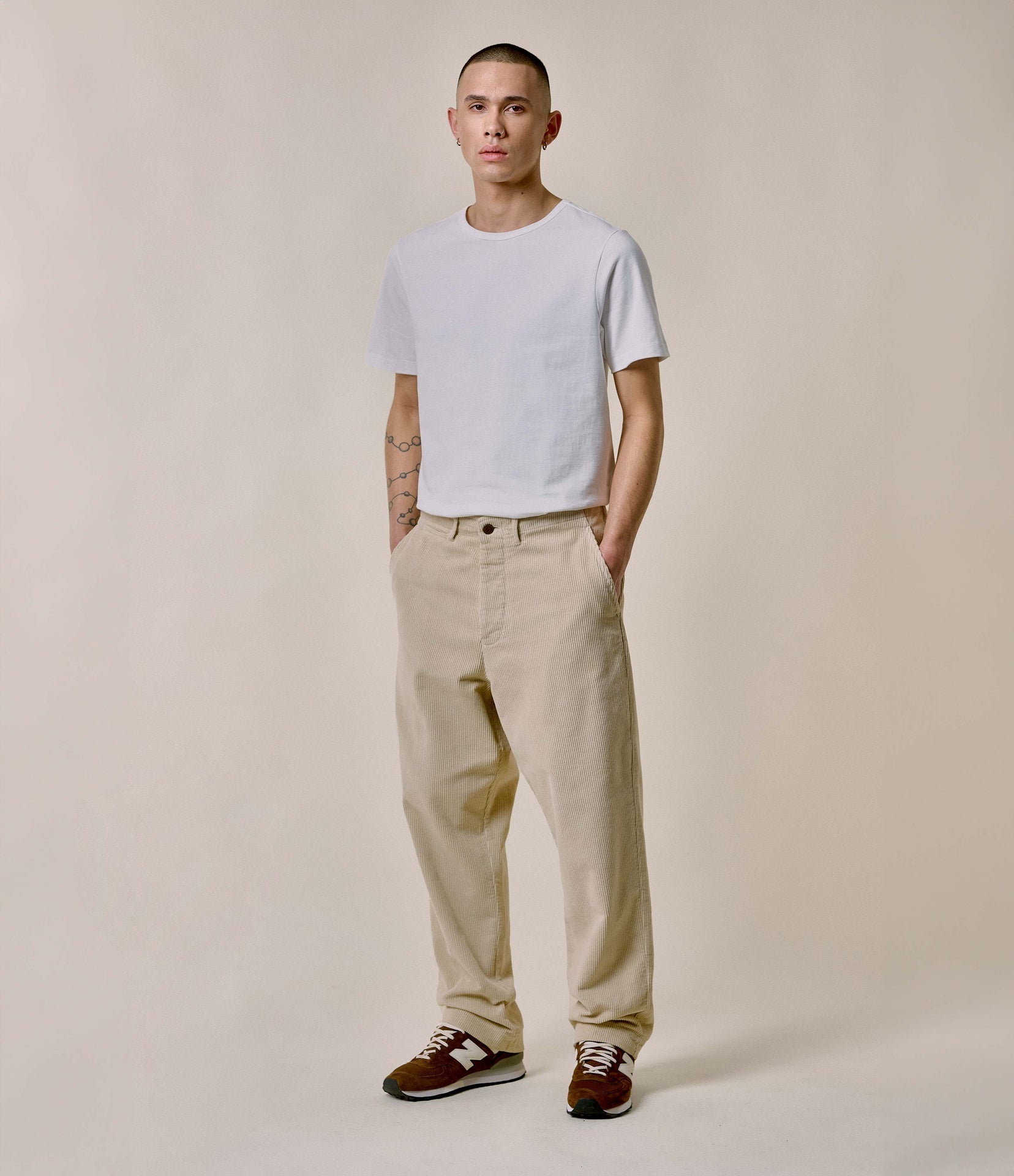 Person wearing a white t-shirt and beige pants against a plain background