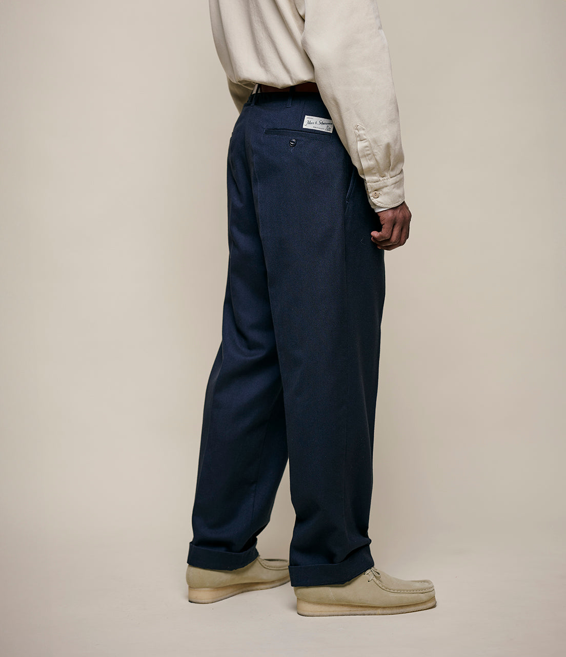 Person wearing navy pants and a light-colored shirt on a plain background