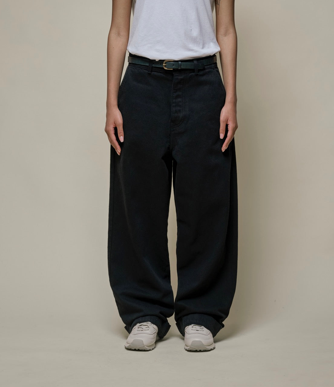 Person wearing black wide-leg pants and a white shirt against a plain background.