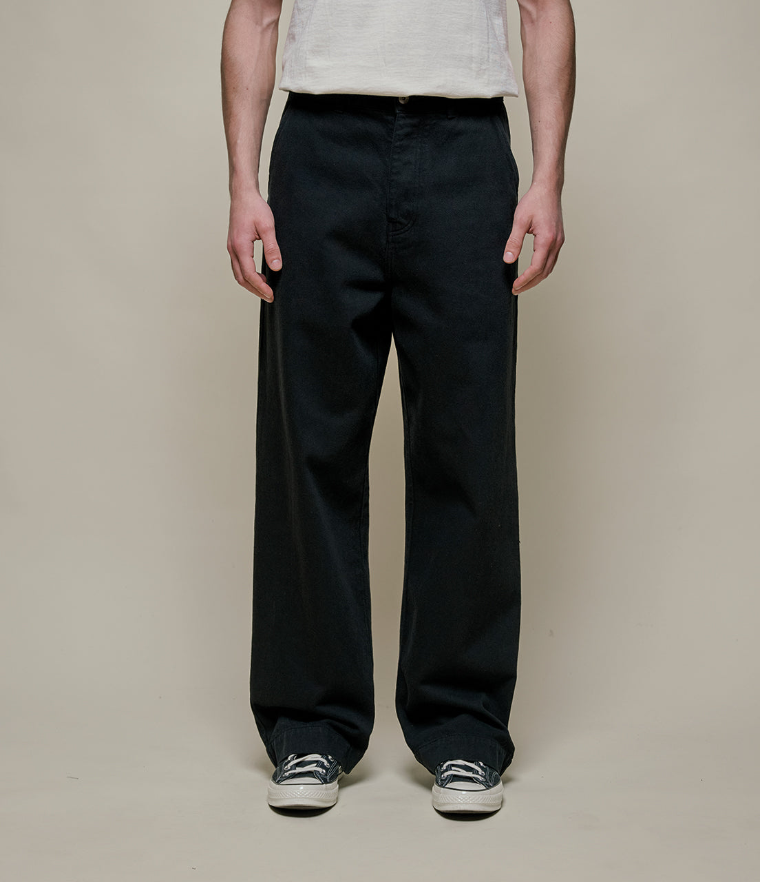 Person wearing black pants on a plain background