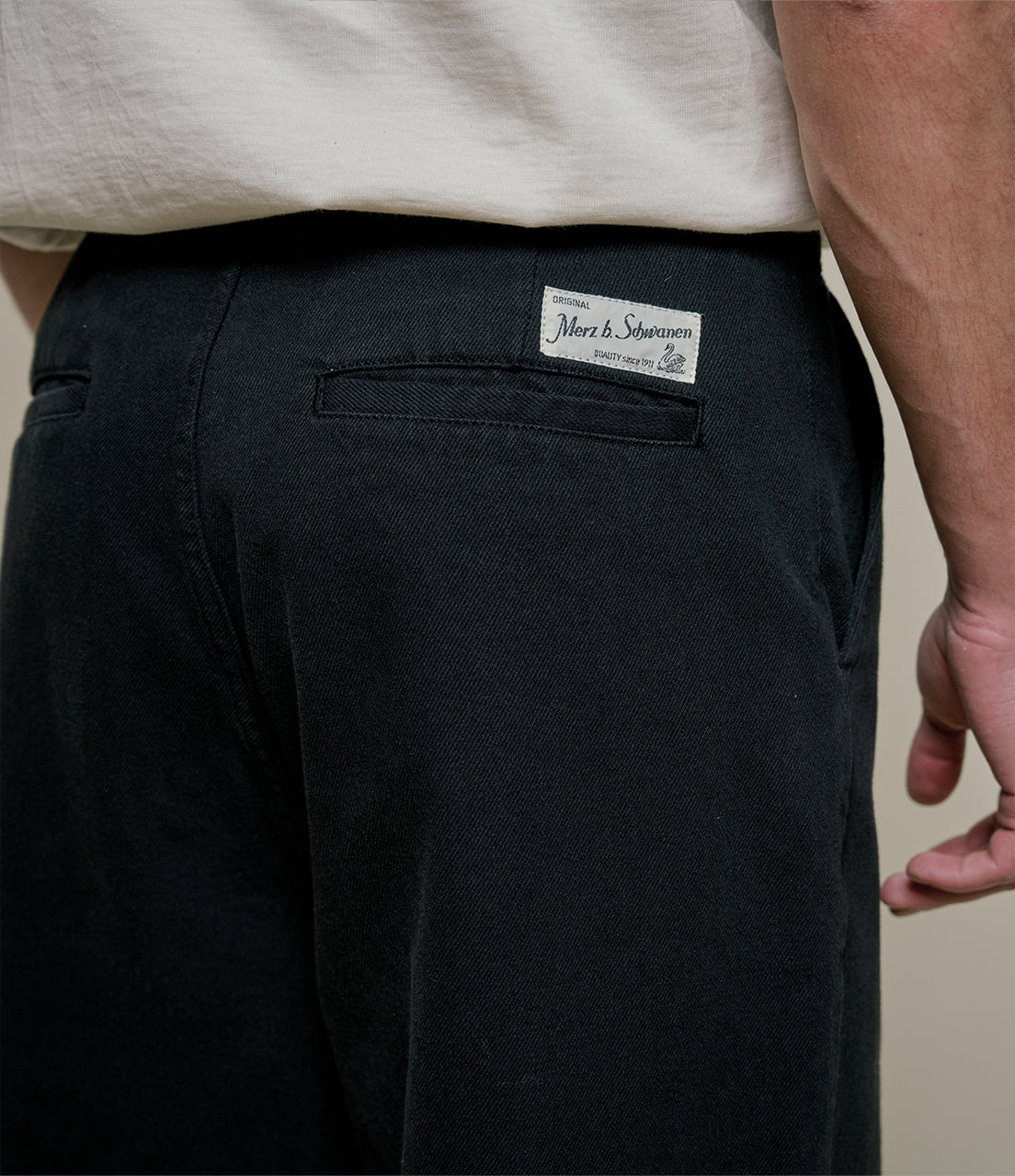 Black pants with a brand label on the back pocket against a neutral background
