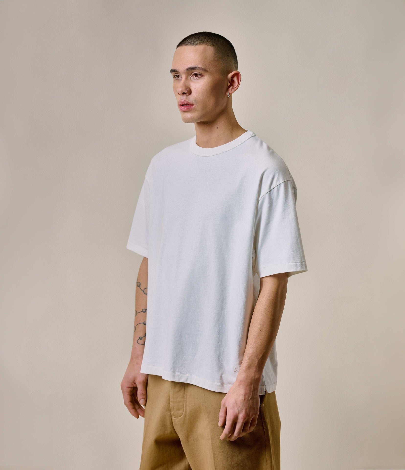 A person wearing a white oversized crew-neck T-shirt with a relaxed fit and short sleeves.