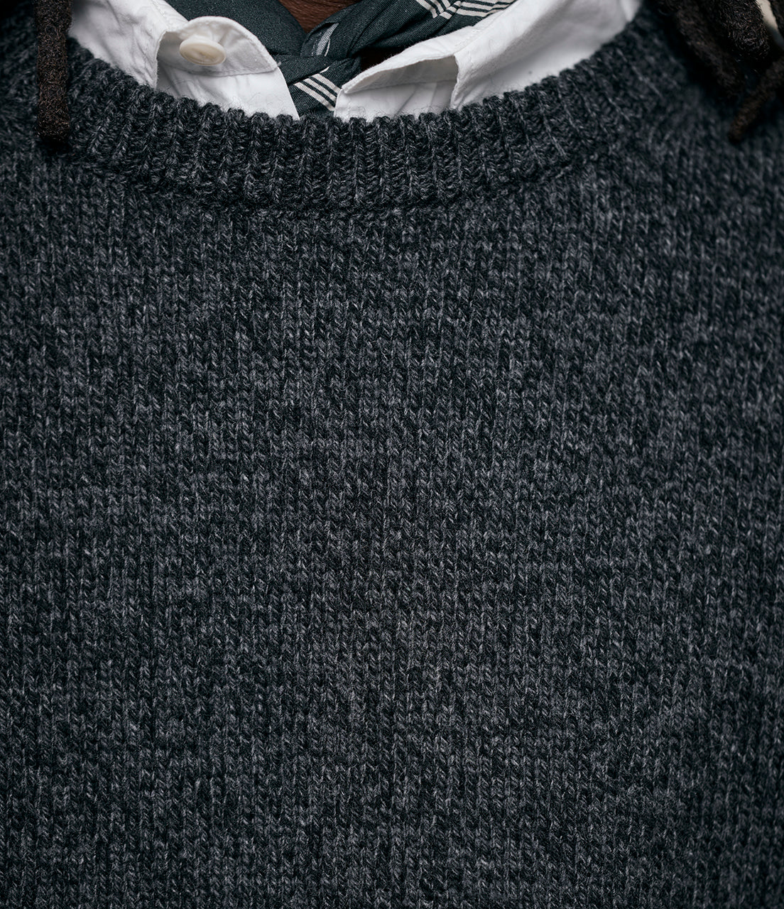 Close-up of a dark gray sweater with a white shirt collar peeking out.