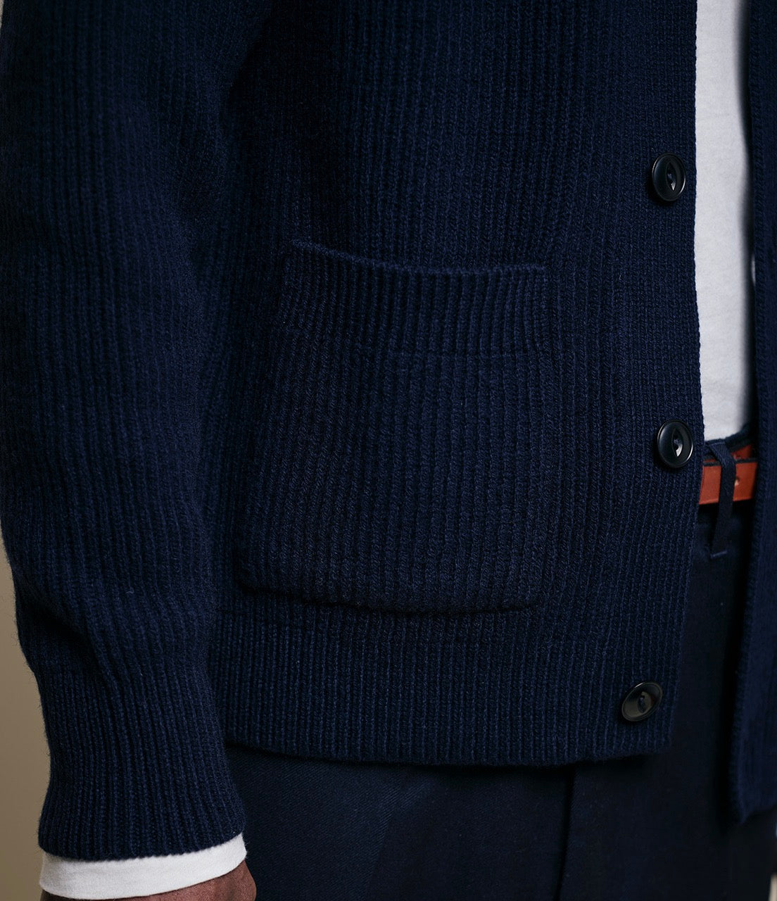 Navy blue cardigan with button details on a neutral background