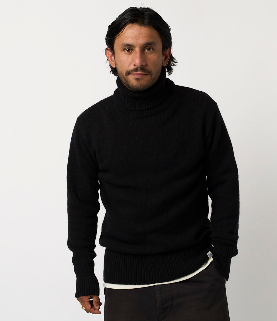 Man wearing a black turtleneck sweater against a white background
