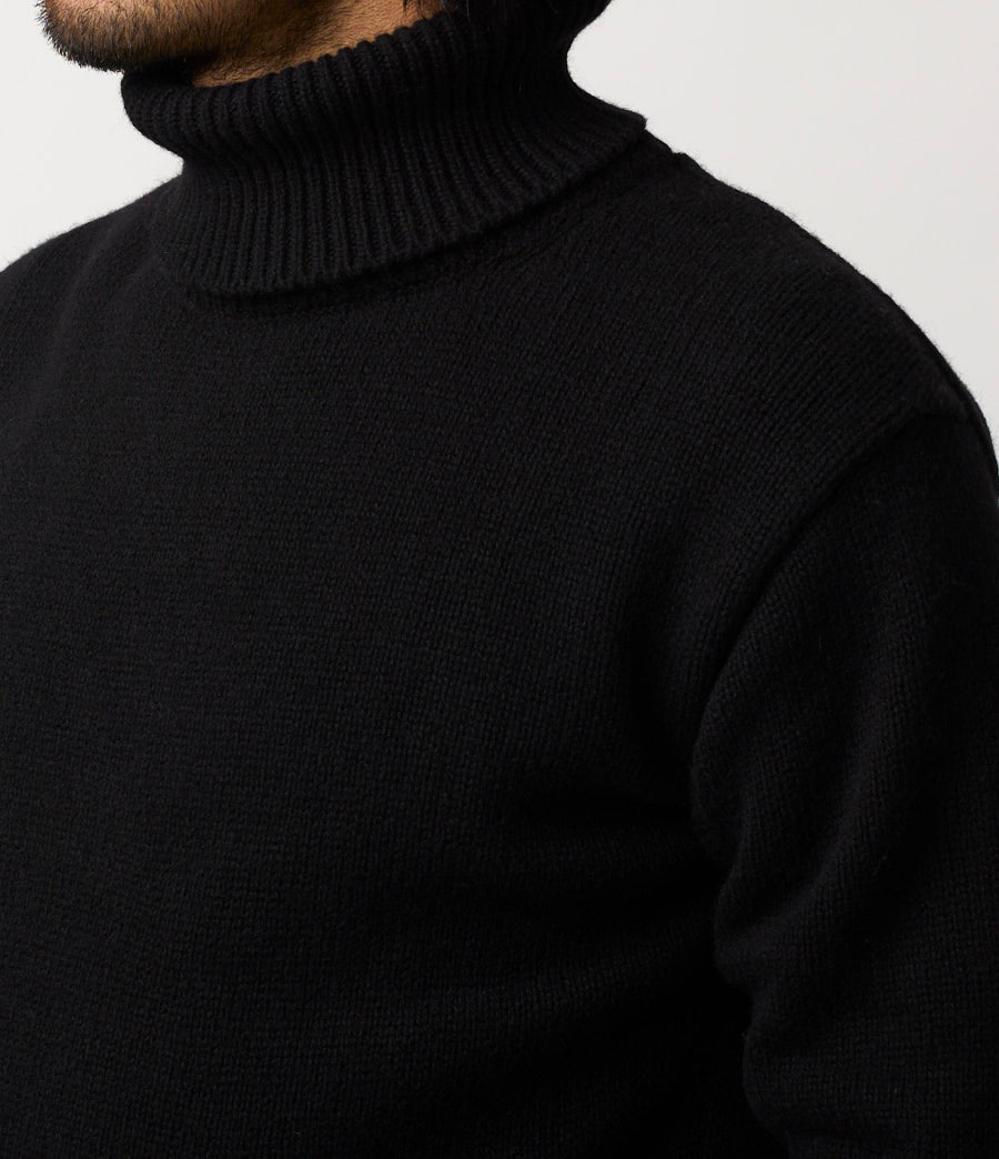 Black turtleneck sweater worn by a person on a light gray background