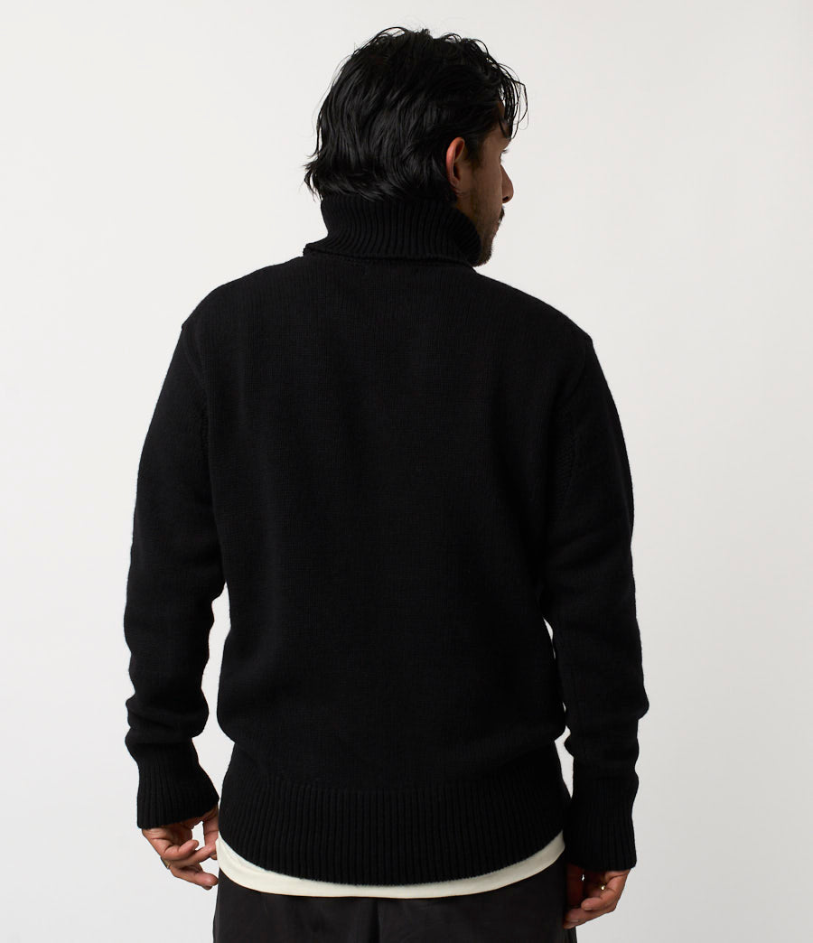 Person wearing a black sweater against a white background