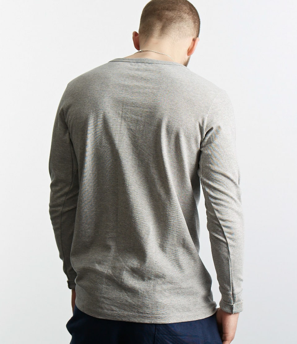 Person wearing a gray long-sleeve shirt against a white background