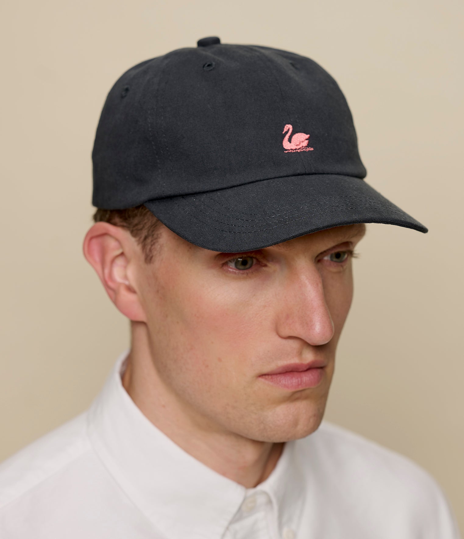 Man wearing a charcoal cap with a rosewood logo on a beige background