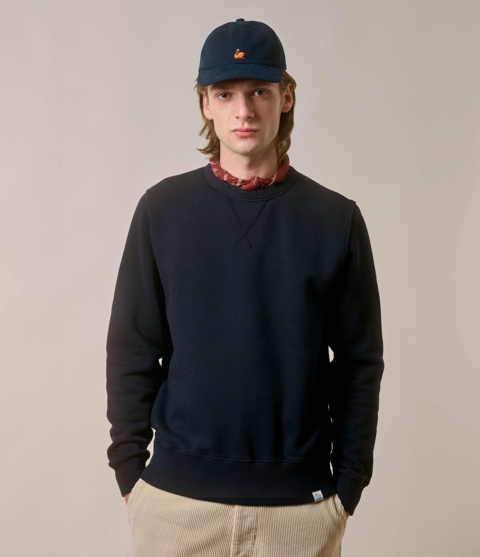 A person wearing a navy fleece sweatshirt with a brushed interior, a cap, and light-colored pants.