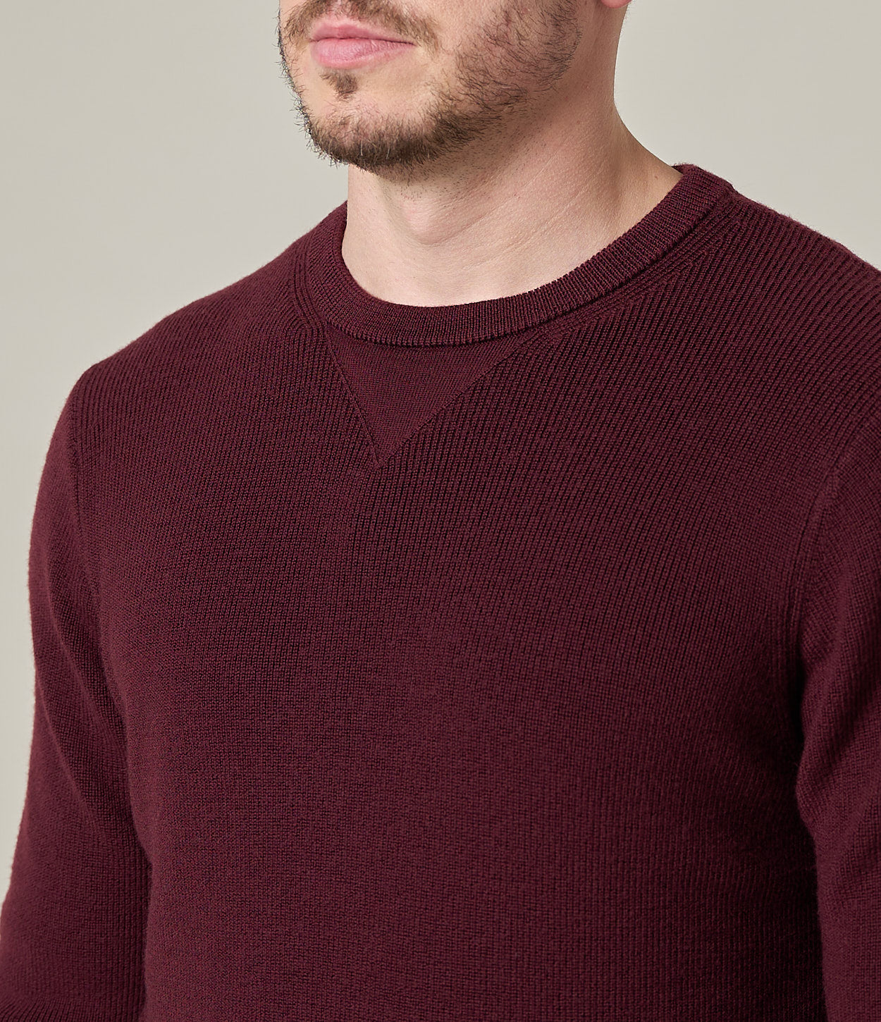 Man wearing a burgundy sweater against a neutral background