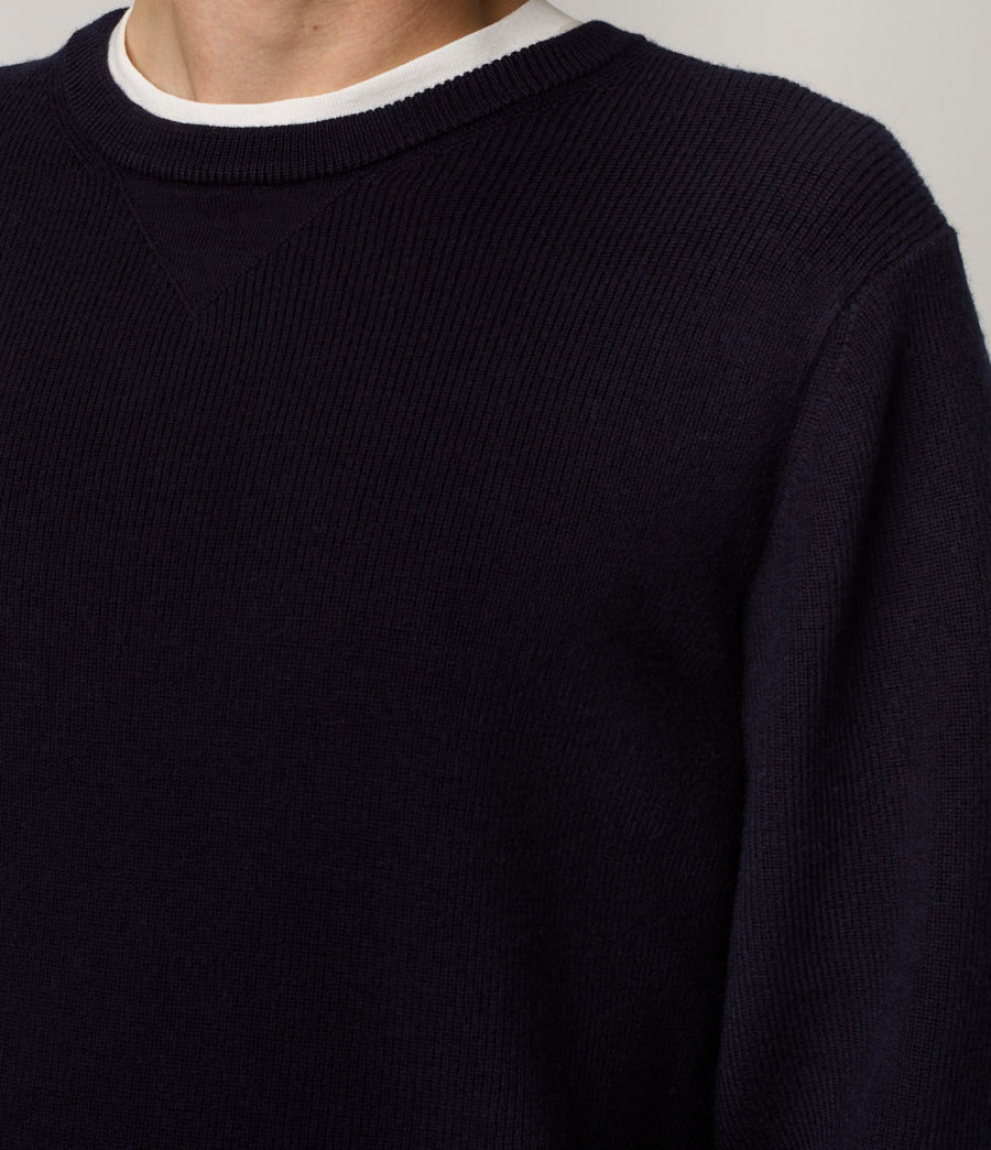 Navy blue sweater with white trim on a neutral background