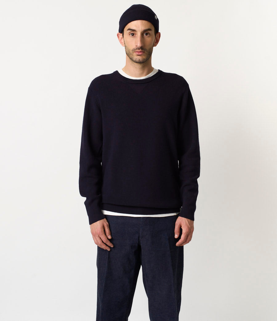 Man wearing a dark navy sweater and pants on a white background