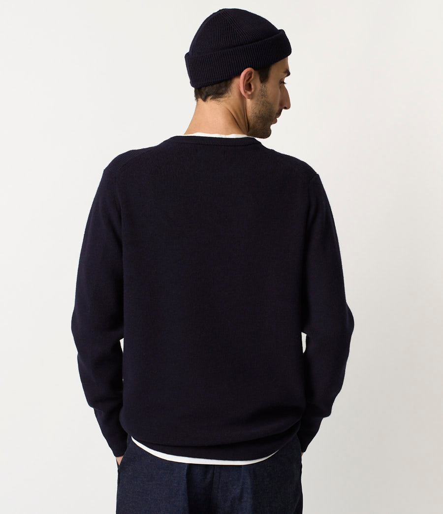 Man wearing a navy blue sweater and beanie against a white background
