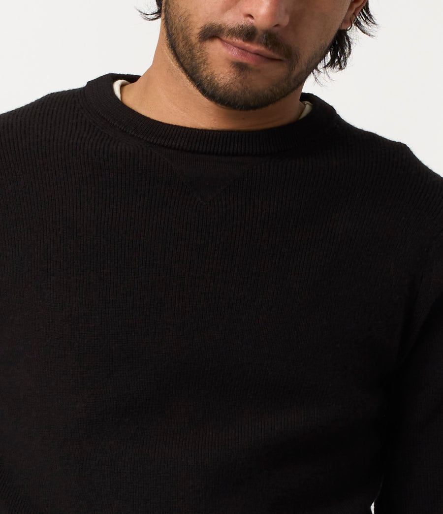 Close-up of a person wearing a black sweater against a white background