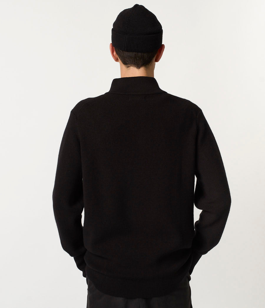 Person wearing a black sweater and beanie from behind on a white background