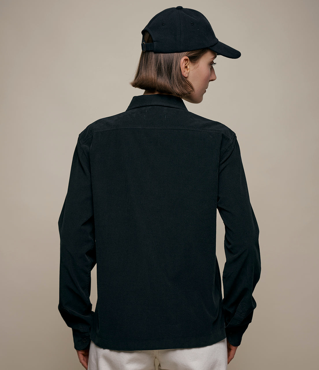 Woman wearing a black shirt and cap on a beige background