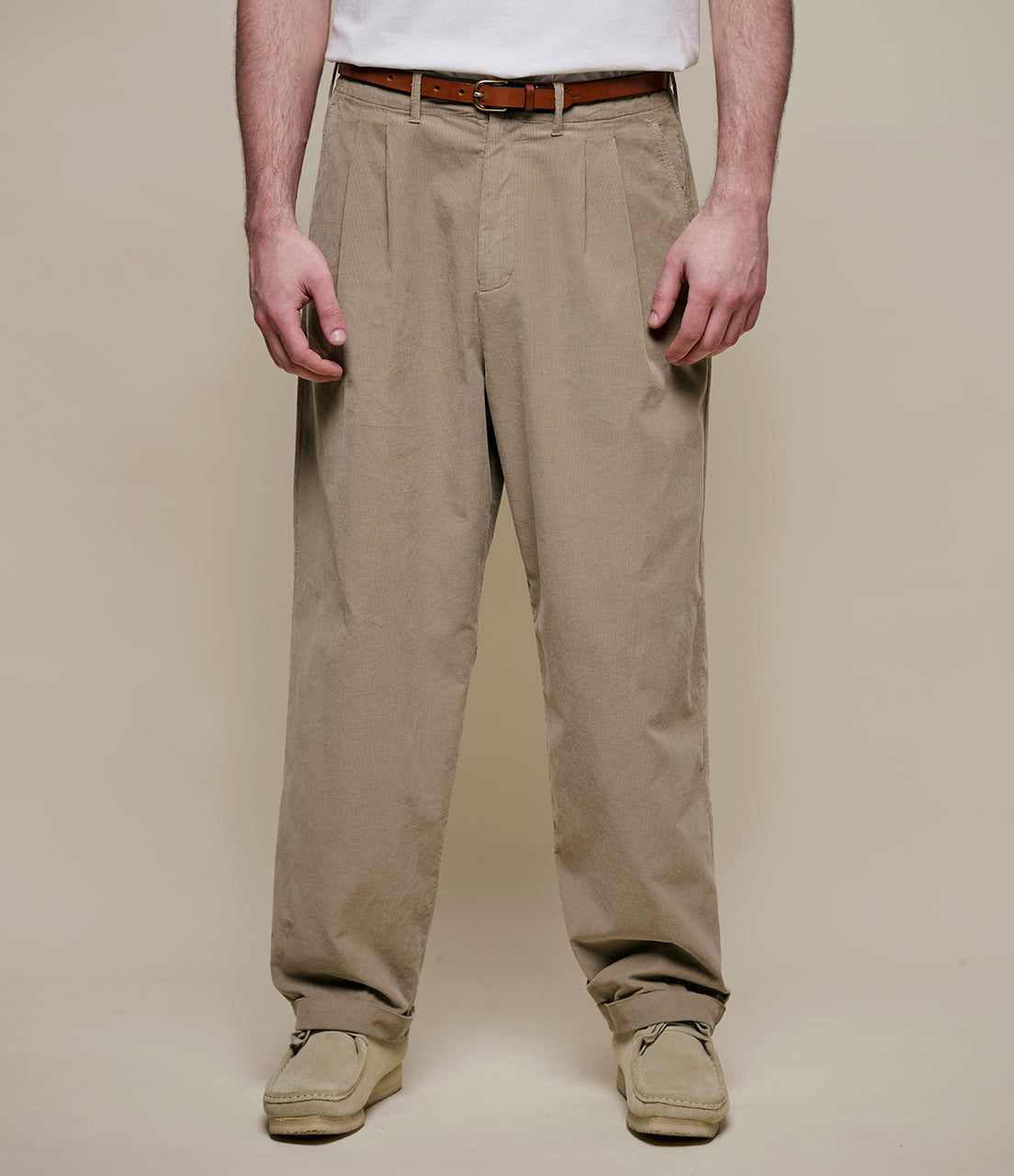 Person wearing beige corduroy pants and a white shirt on a plain background