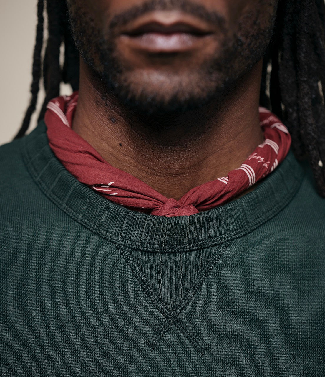 Person wearing a green sweater and red bandana with white patterns.