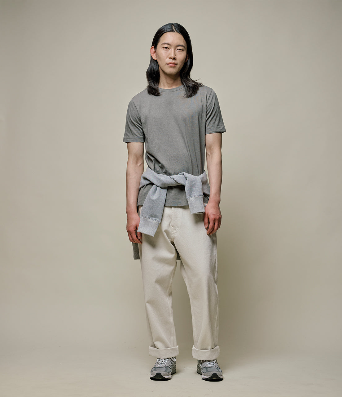 Person wearing a green t-shirt and beige pants against a plain background