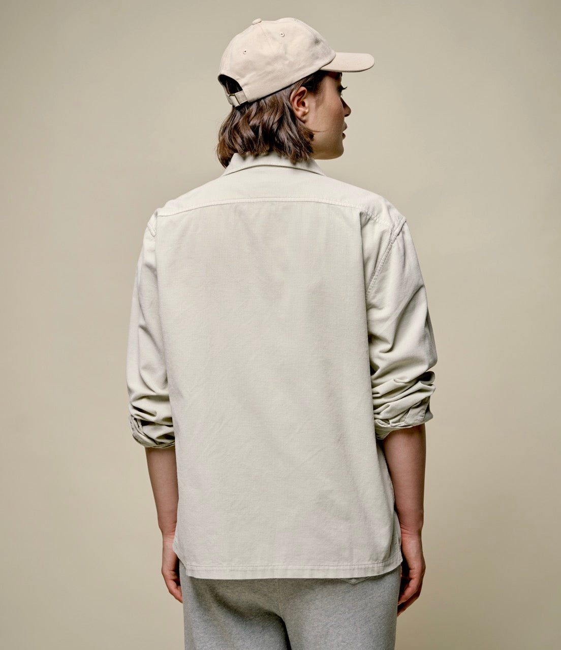 woman wearing a beige corduroy shirt and beige cap