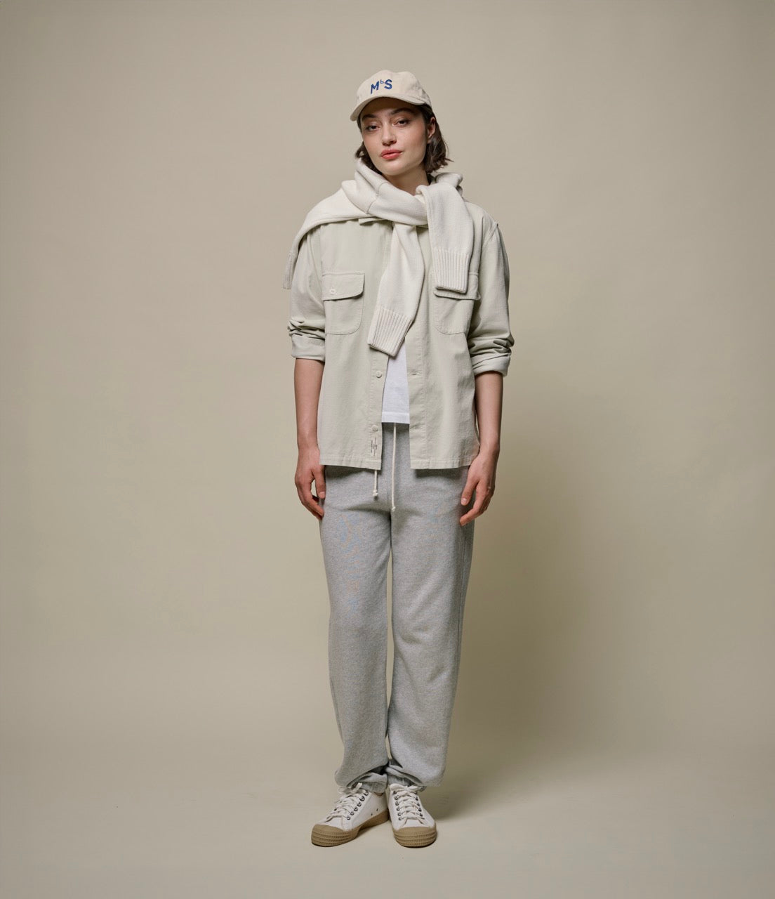 woman wearing a beige corduroy shirt over a white T-shirt and grey sweatpants