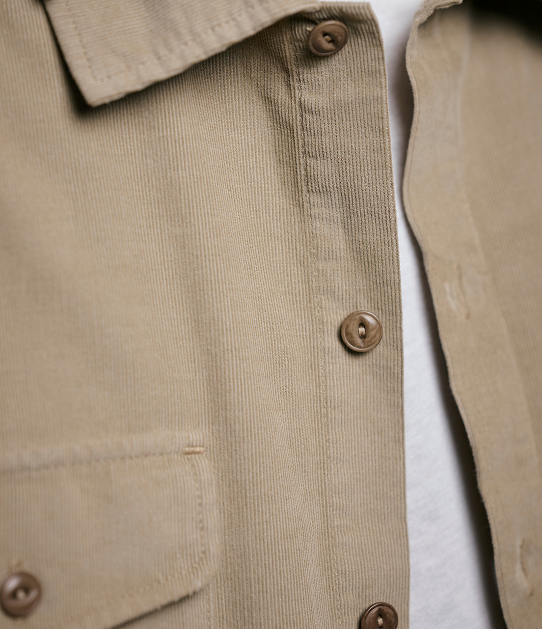 Close-up of a beige corduroy shirt with buttons on a white background