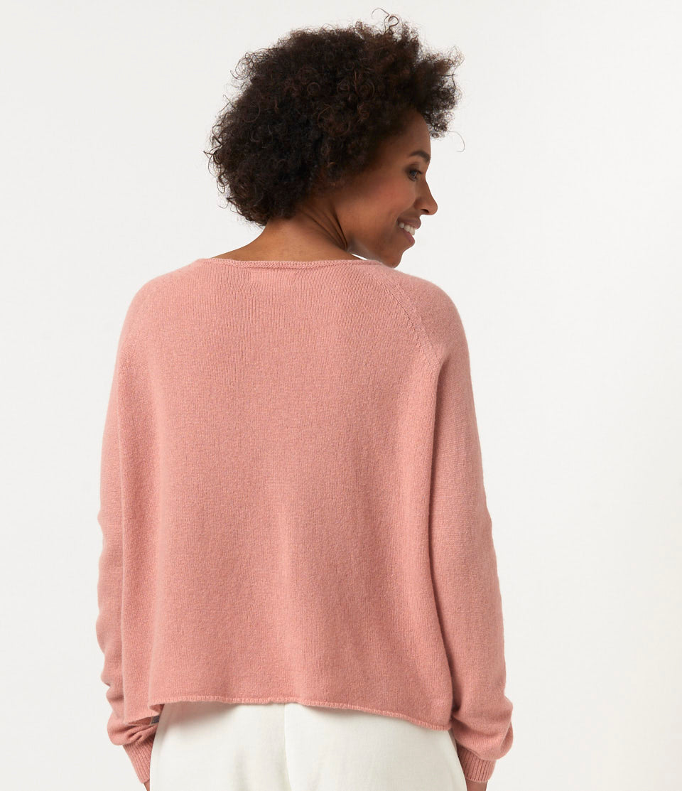 Person wearing a pink sweater against a plain background
