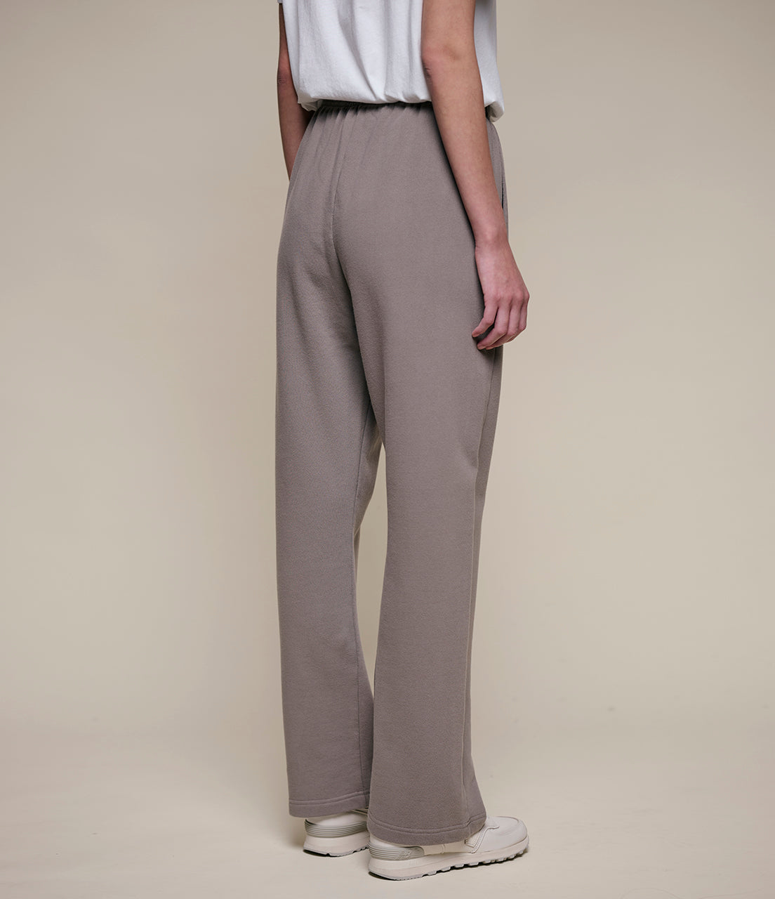 Person wearing beige wide-leg pants on a plain background