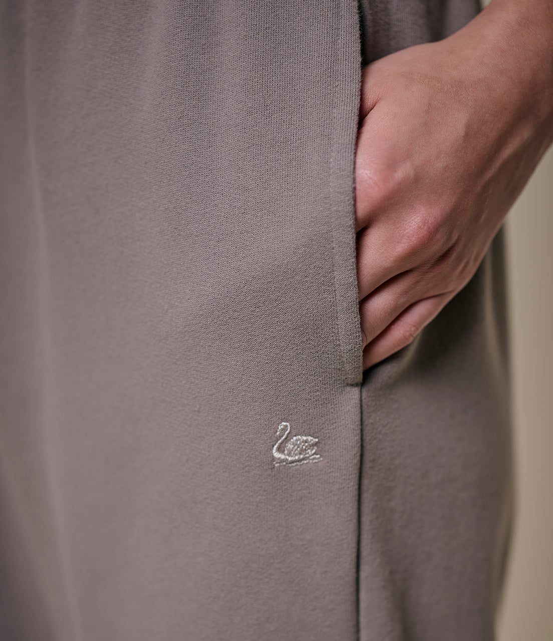 Close-up of a gray garment with a small logo on a neutral background