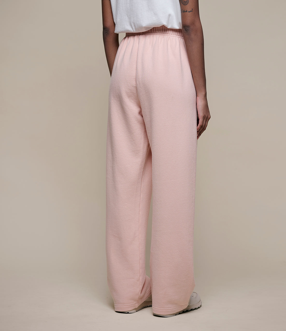Person wearing light pink pants on a beige background