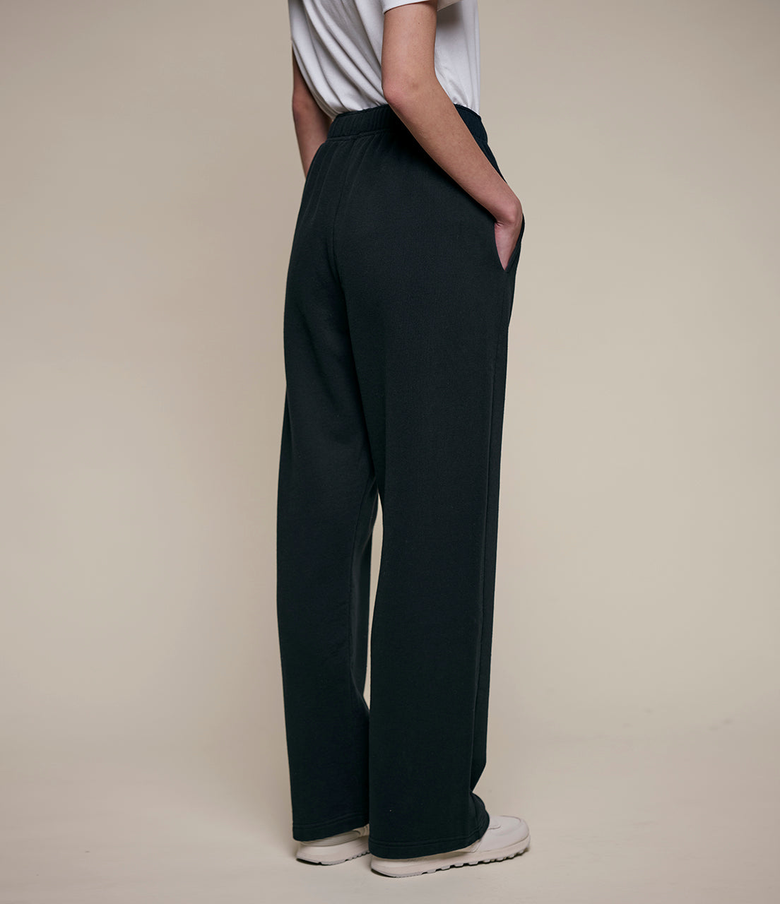 Person wearing black wide-leg pants on a beige background