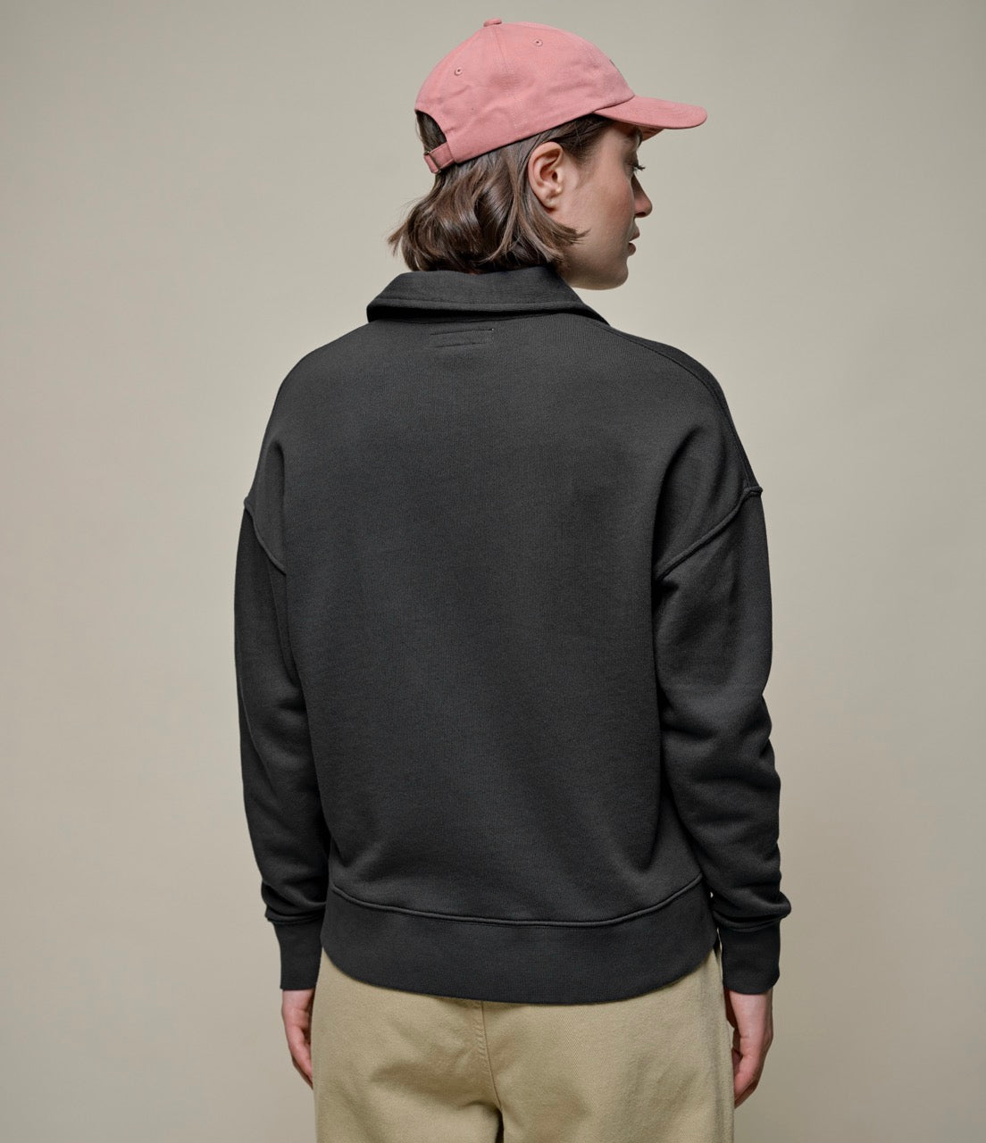 Backside of person wearing dark grey sweatshirt and khaki pants