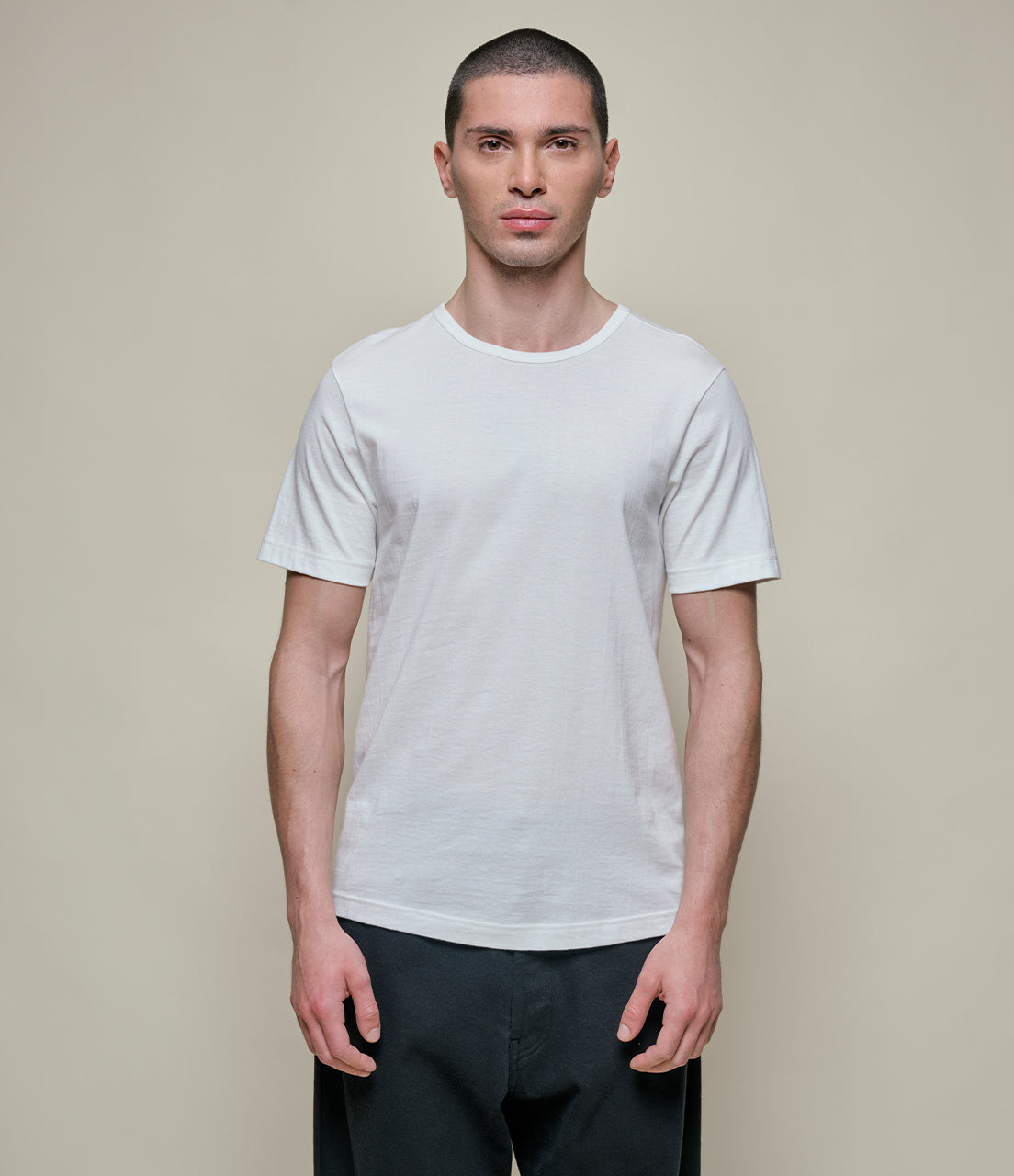 Man wearing a plain white t-shirt against a neutral background