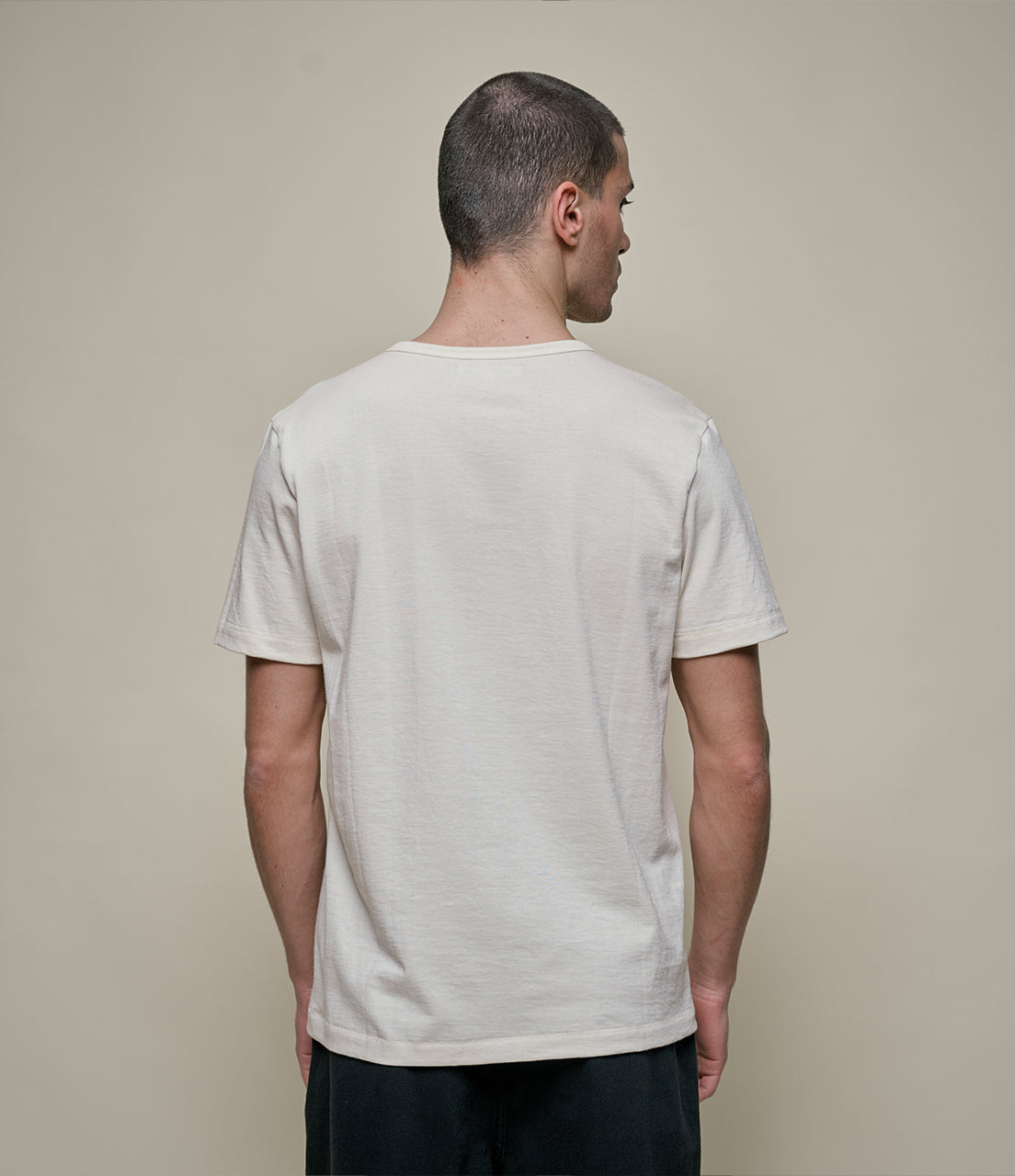 Man wearing a beige t-shirt against a beige background