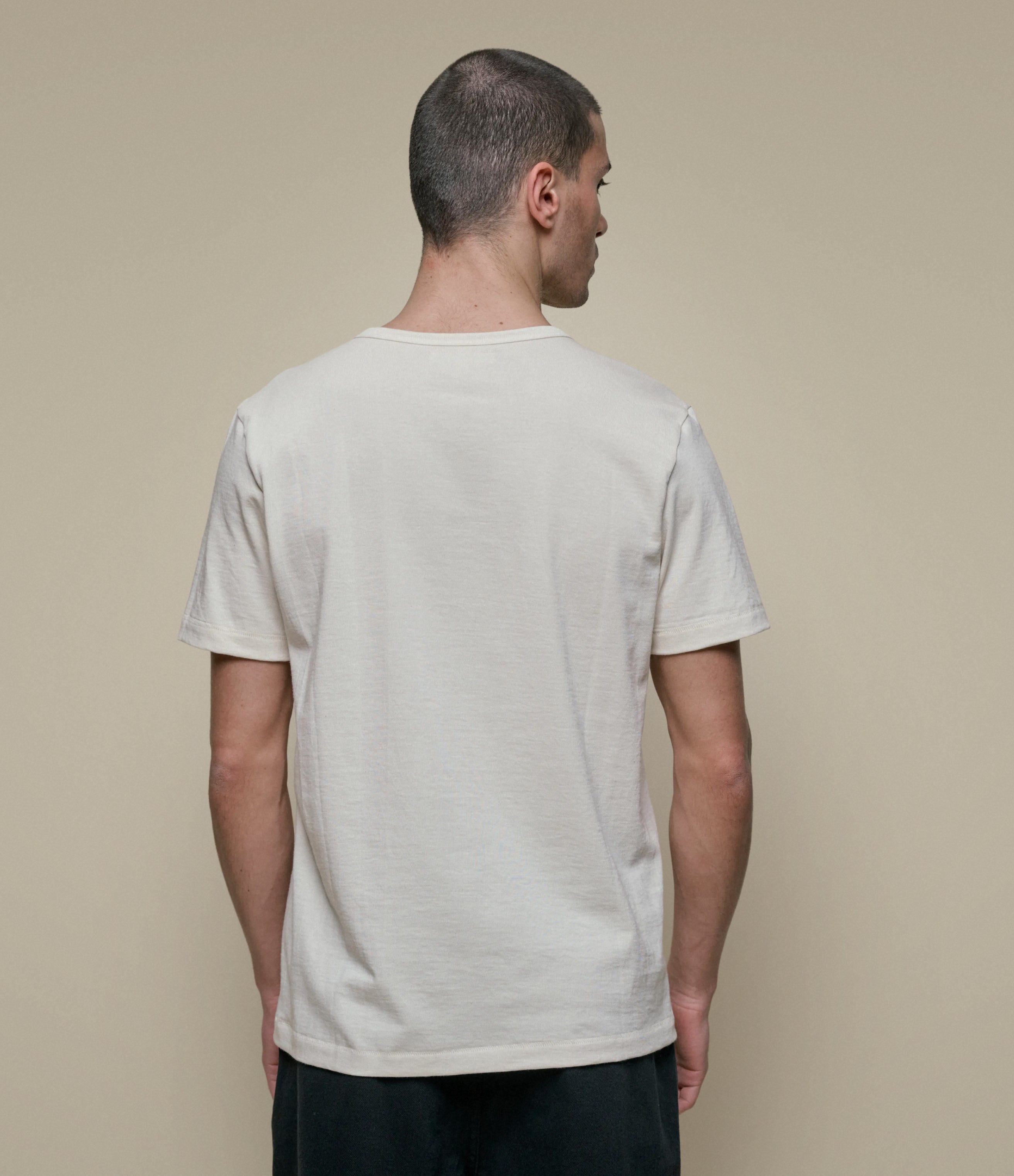 Man wearing a beige t-shirt against a beige background